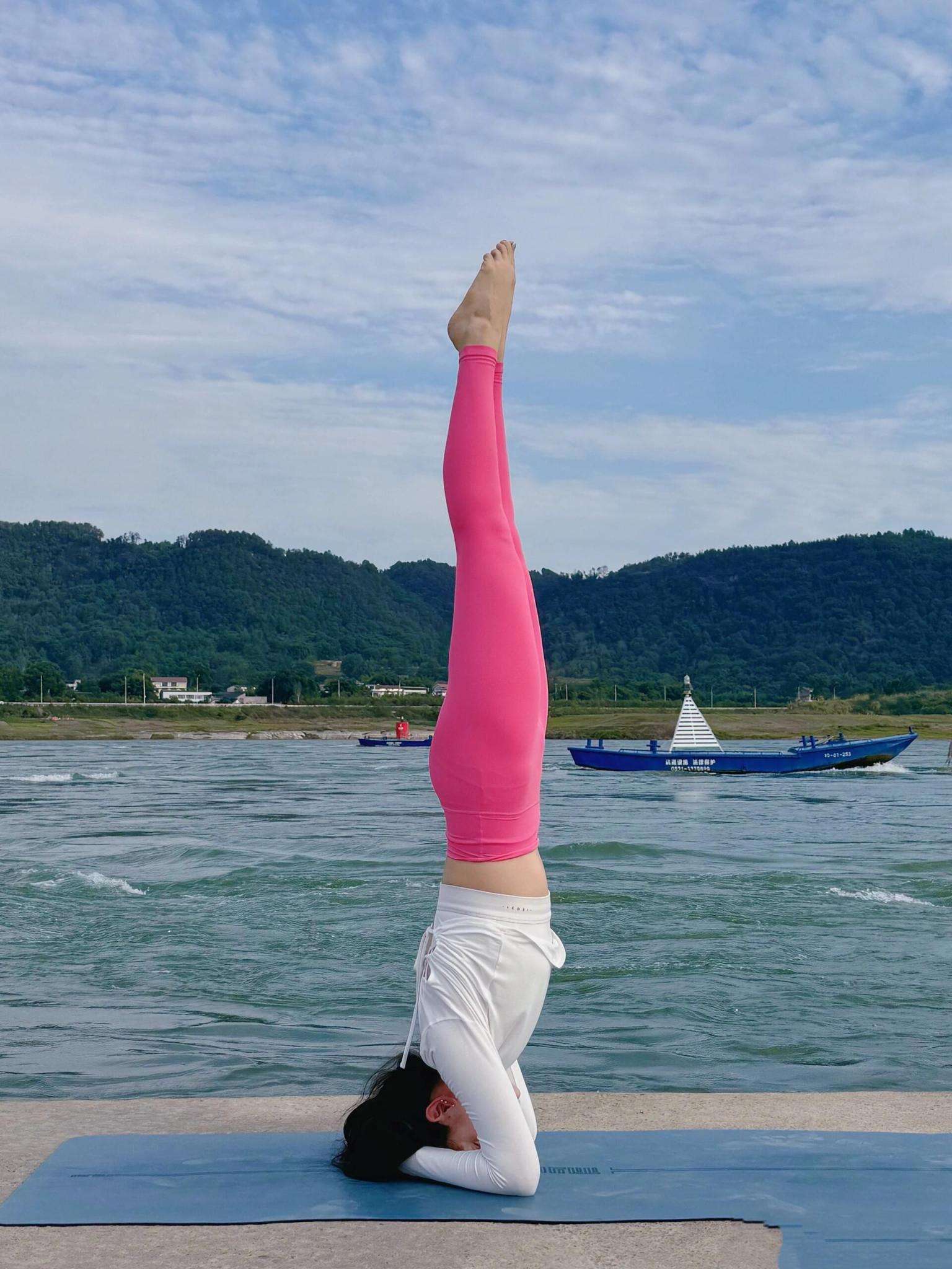 瑜伽教练河边练习头倒立展现曼妙身姿 Yoga instructor practices headon standing by the river to show graceful posture