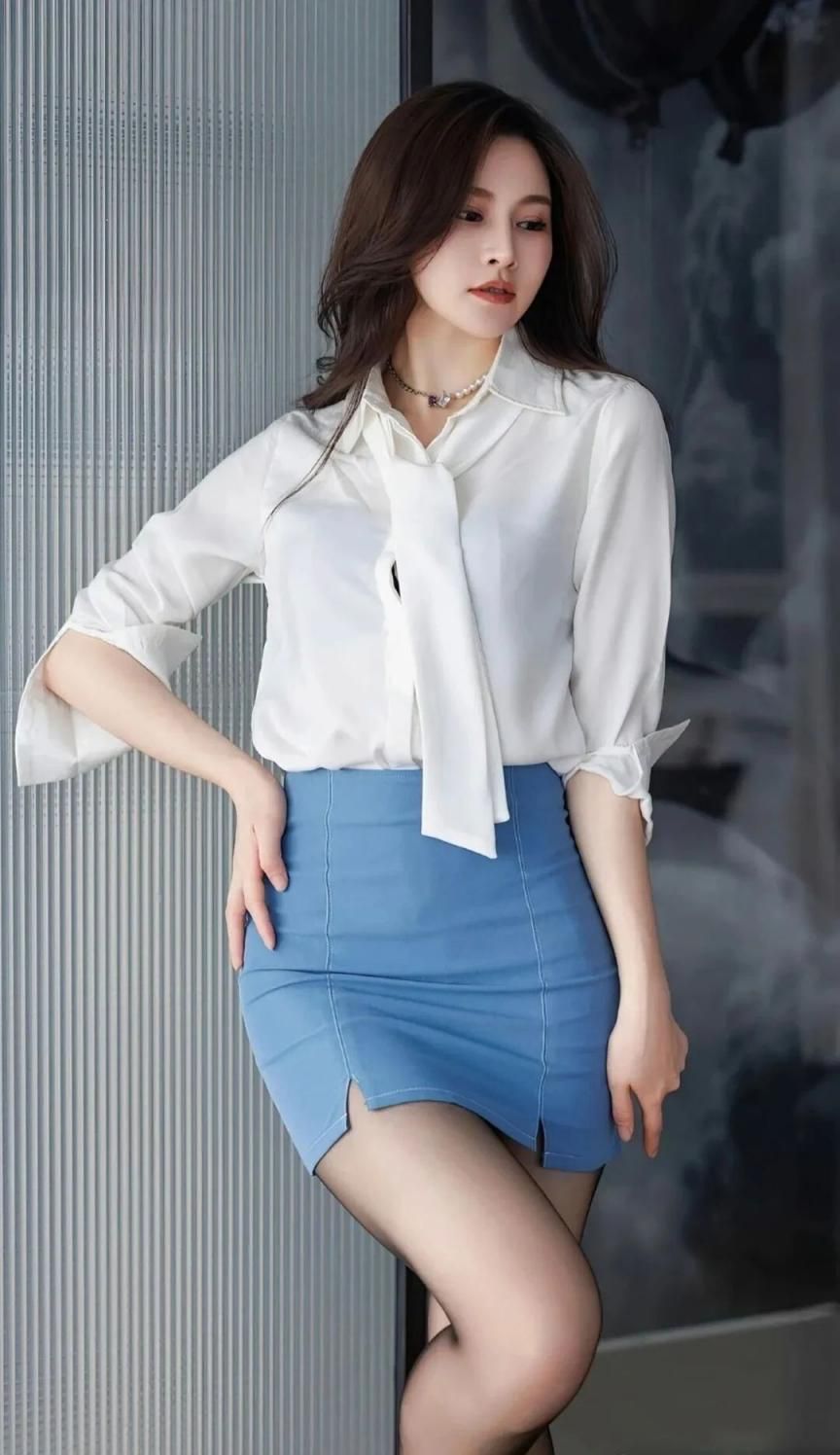 魅力女性身着经典白衬衫搭配蓝色短裙尽显时尚品味 Charming woman w
