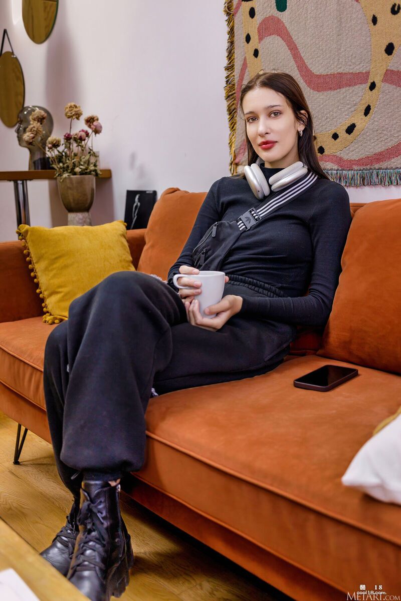 她赤身裸体地坐在沙发上，面带微笑 She is sitting naked on